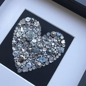 silver sparkly heart button art on black background. Framed picture.